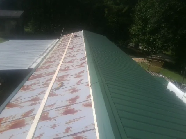 Old rusted panels beside newly installed green metal roofing — Wind Damage Roof Repair by Roofing Brothers in Alcoa