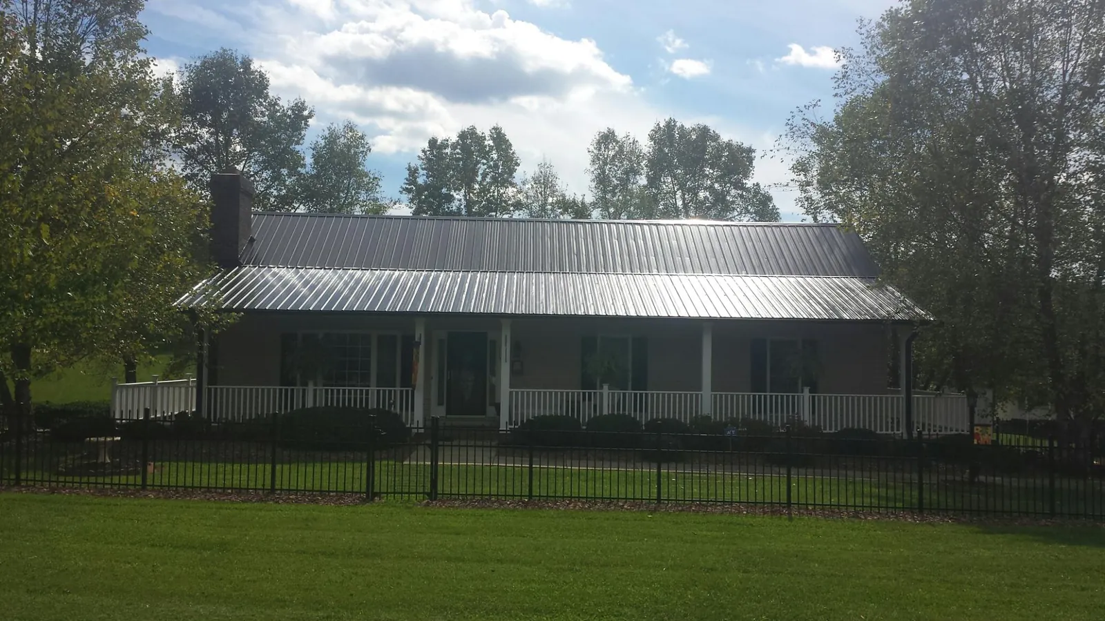 Gray metal roof on a brick ranch with a full width front porch — Gutter Guard Installation work by our crew in Alcoa