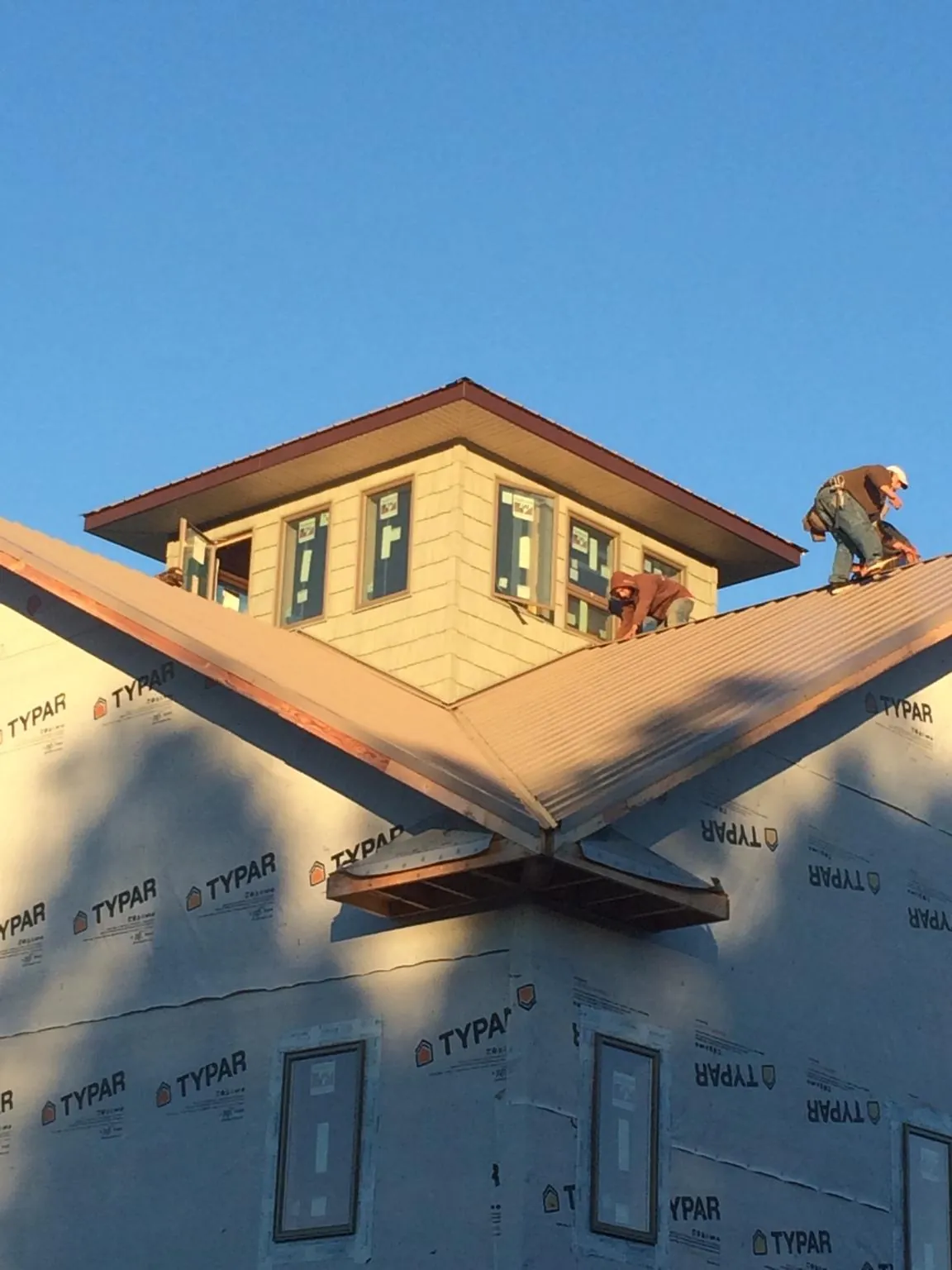 Roofers working around a rooftop cupola on a new metal roof at sunset — Roof Waterproofing in Alcoa by Roofing Brothers